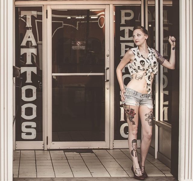 Tattooed woman standing in entrance to tattoo shop.